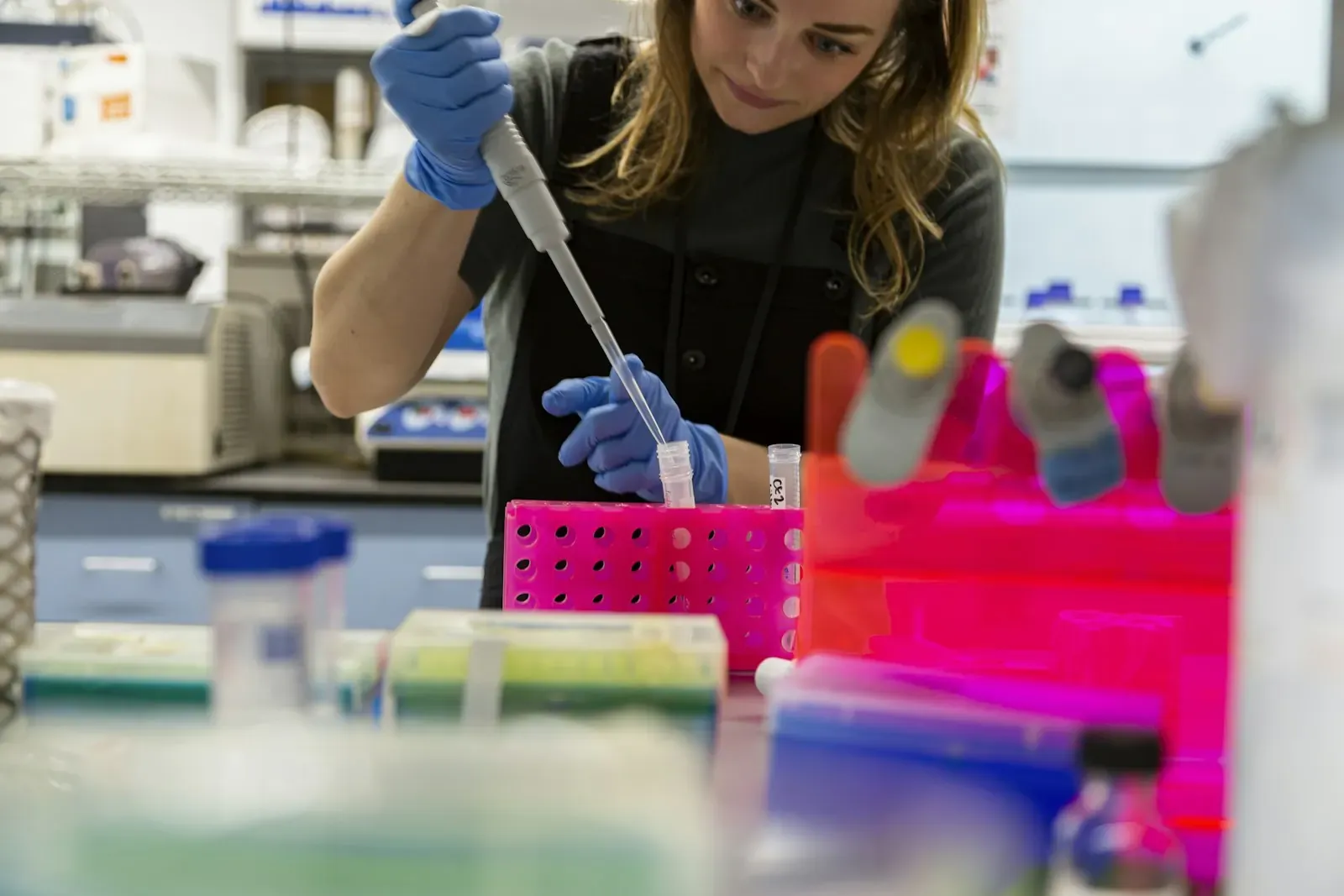 A lab technician with a pipette next to samples in a laboratory